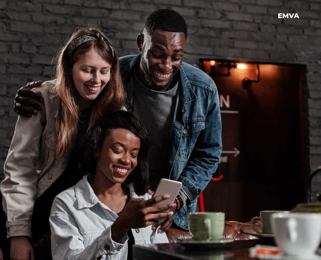 Three people smiling together while looking at a phone